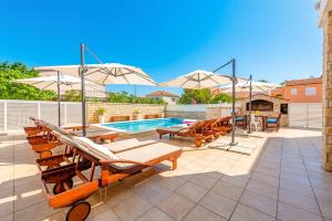 un patio avec piscine, tables et parasols dans l'établissement Villa Karmen - Poolhouse, à Vir
