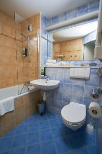 uma casa de banho em azulejos azuis com um WC e um lavatório em Sure Hotel by Best Western Limoges Sud em Feytiat