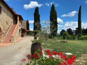 un jardin avec des fleurs rouges, un bâtiment et des arbres dans l'établissement Tenuta Sovestro, à San Gimignano