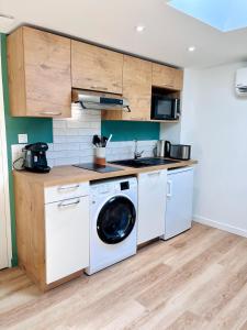 eine Küche mit einer Waschmaschine und einem Geschirrspüler in der Unterkunft LE QUAI 6 - Studio neuf CALME LUMINEUX - CLIM - WiFi - Gare à 200m in Agen
