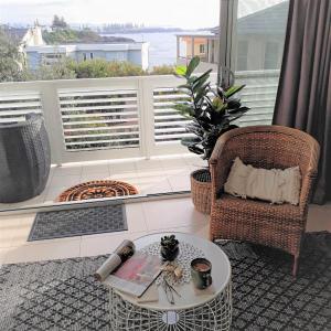 a living room with a table and a chair and a balcony at Shutters-Waterfront-Private-at Little Blowhole in Kiama
