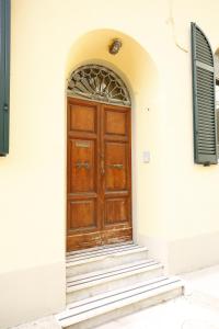 - une porte en bois dans un bâtiment blanc avec des escaliers dans l'établissement Lungarno Buozzi 7 Apartments, à Pise