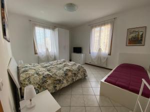 a bedroom with a bed and a couch and windows at Little and cozy flat near Venice in Marghera