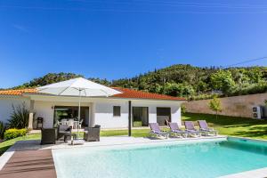 a house with a swimming pool with chairs and an umbrella at Basto Village House - Eco Smart Luxury Villa in Cabeceiras de Basto