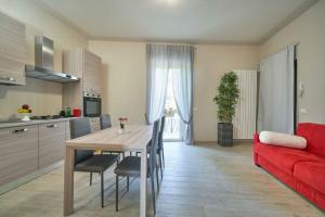 een keuken en een woonkamer met een rode bank en een tafel bij CASA TRAMONTO in Sulzano