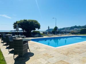 una piscina con sillas y una mesa junto a ella en La Haule Manor en Saint Aubin