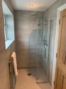 a shower with a glass door in a bathroom at Highfield Coach House in Lymington