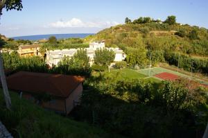 een tennisbaan op een heuvel met huizen bij Hotel Villaggio Old River in Capo Vaticano