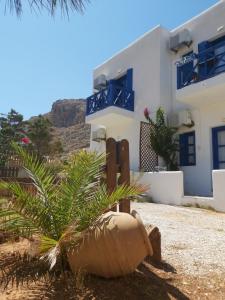 a house with a palm tree in front of it at Aegean Star Hotel in Karavostasi