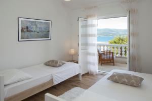een witte slaapkamer met 2 bedden en een balkon bij Situs Katarina in Trogir