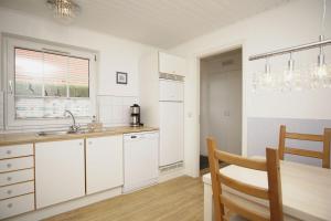 a kitchen with white cabinets and a sink and a table at Ferienhaus Wiking Haus - Terrasse und Garten in Binz