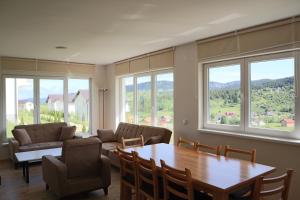 a living room with a table and chairs and windows at Lotus Villas in Travnik