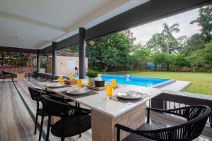 een patio met een tafel en stoelen en een zwembad bij Sunshine Bloom by StayVista - Your Oasis with Pool, Lawn, Gazebo, and Poker Table in Lonavala