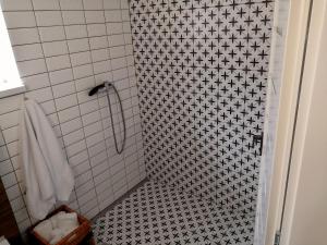 een badkamer met een douche met zwarte en witte tegels bij Apartmány RŮŽIČKA in Mikulov