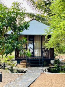 a house with a porch and a pond in front of it at Kaaya Eco Resort Yala in Tissamaharama