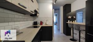 a kitchen with black cabinets and white tile walls at CITY VIEW Tołstoja - KLIMATYZACJA in Świdnica