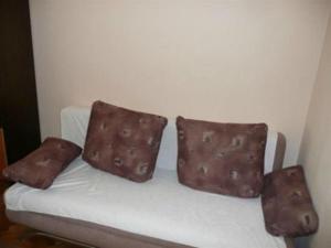 drei braune Kissen auf einer weißen Couch in der Unterkunft Apartments Pičuljan 2829 in Rab
