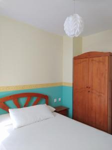 1 dormitorio con 1 cama y armario de madera en Chalet adosado con azotea andaluza y patio, junto a la playa, en Isla Cristina