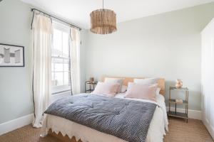 um quarto branco com uma cama com almofadas cor-de-rosa em Fig Tree House, family friendly, 1 min Sea em Kent