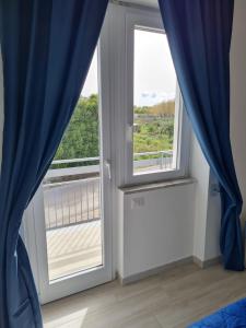 een kamer met een raam met blauwe gordijnen bij B&B Rayl in Formia