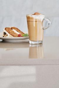 a glass of coffee next to a plate of cake at Helios Mallorca Hotel & Apartments in Can Pastilla