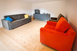 a living room with an orange chair and a couch at La Marmote Albergo Diffuso di Paluzza Aip in Paluzza