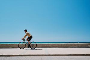 a person riding a bike on a sidewalk near the ocean at Helios Mallorca Hotel & Apartments in Can Pastilla