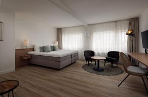 - un salon avec un lit, une table et des chaises dans l'établissement WestCord Hotel de Wadden, à Oost-Vlieland