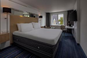 uma grande cama branca num quarto de hotel em WestCord Hotel de Wadden em Oost-Vlieland