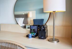 a mirror on a wooden table with a lamp at WestCord Hotel de Wadden in Oost-Vlieland