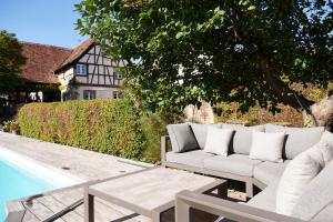 a couch and a table next to a pool at La Cour de Lise Maison D'Hôtes et SPA in Willgottheim