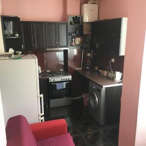a small kitchen with a stove and a refrigerator at Apartment Urushadze in Batumi