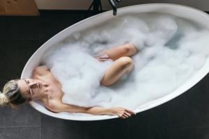 Eine Frau in einer Badewanne voller Wolken in der Unterkunft feelfree - Natur & Aktiv Resort Ötztal in Oetz