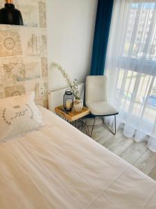 a bedroom with a bed and a chair and a window at Apartament Batorego 713 in Gdynia