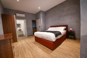 a bedroom with a large bed and a bathroom at Quaint Boutique Hotel Sannat in Sannat