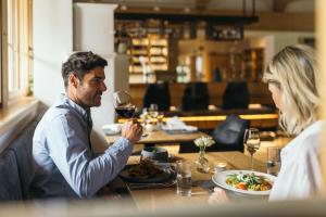 a man and woman sitting at a table with a glass of wine at feelfree - Natur & Aktiv Resort Ötztal in Oetz