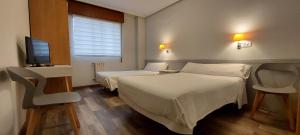 una camera d'albergo con due letti e una televisione di Pensión Romero a Oviedo