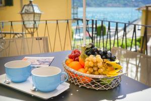 un bol de fruits assis sur une table avec deux tasses dans l'établissement Hidden Terrace With Lake View, à Dongo