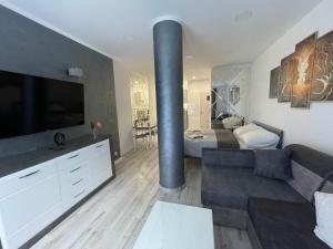 a living room with a couch and a large television at Apartamenty "SZKIEŁKO" in Koszalin