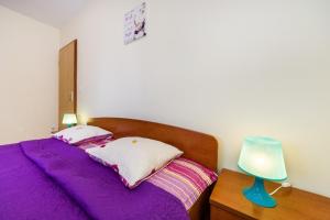 a bedroom with a bed with purple sheets and a lamp at Apartment Vrsi at the Beach in Vrsi +93 photos
