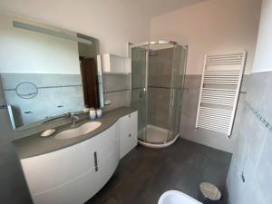 een badkamer met een wastafel, een douche en een spiegel bij Casa Enza: appartamento a un passo dal mare. in Bordighera