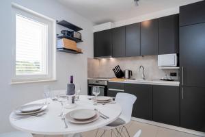 a kitchen with a white table and chairs in a kitchen at Apartments Mistral in Bol