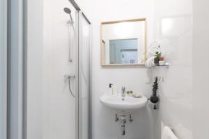 biała łazienka z umywalką i lustrem w obiekcie Yeshello Vienna Central Station Apartment w Wiedniu
