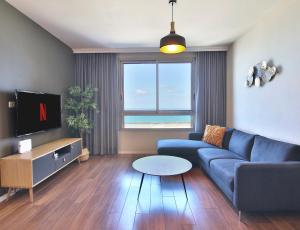 a living room with a blue couch and a tv at Luxury Suites by Notaly Ariel - Carmel Beach in Haifa
