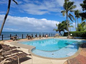 a swimming pool with chairs and the ocean in the background at Solar dos Arcos in Praia do Forte