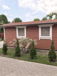 a red house with trees in front of it at Namelis ,,Gilė” in Šventoji