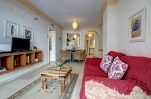 マルベーリャにあるFirst Line Beach Apartmentの赤いソファとテーブルのあるリビングルーム