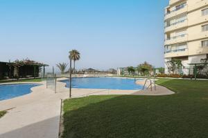 マルベーリャにあるFirst Line Beach Apartmentのアパートメントの建物の前にスイミングプールがあります。