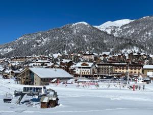 una città nella neve con montagne sullo sfondo di Le Janus, pied des pistes, 2 garages, terrasse avec sauna a Monginevro