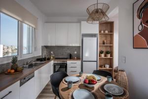 een keuken met een tafel en stoelen en een keuken met witte kasten bij Khroma Luxury Suite 2 Beach front apartment in Chersonissos